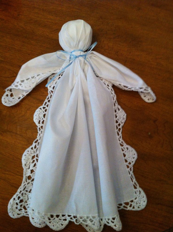 a white dress with blue ribbon and lace on the bottom is sitting on a wooden table