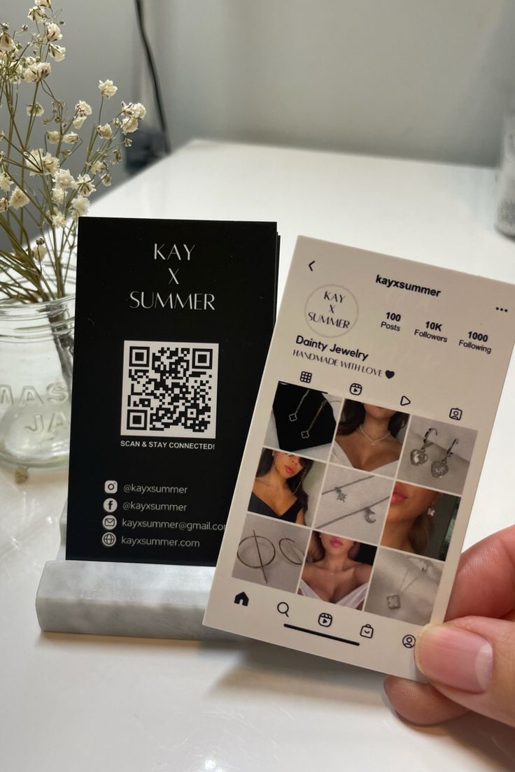 a person holding up a business card with pictures on it and qr code attached to the front