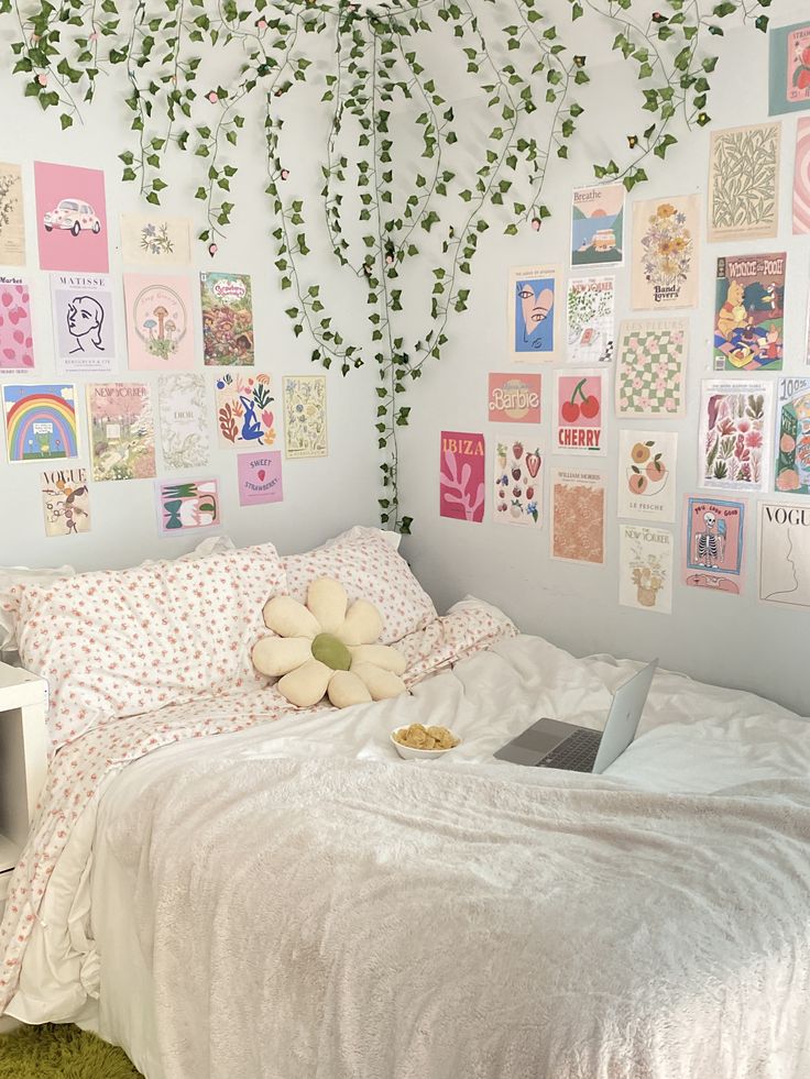 a bed with white sheets and pillows in front of a wall covered with pictures on it