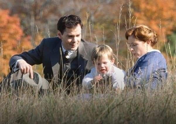 a man, woman and child sitting in tall grass