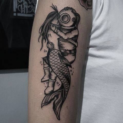 a man with a tattoo on his arm is holding a fish and looking at the camera