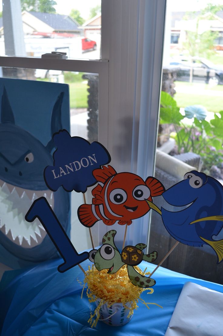 an ocean themed birthday cake on a blue table cloth with decorations in the shape of fish