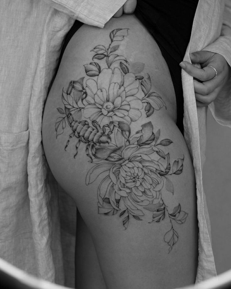 a woman's thigh with flowers on it and leaves around the thighs, in black and white