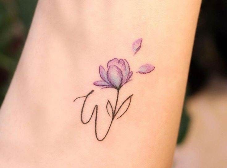 a small tattoo on the ankle of a woman's foot with a pink flower