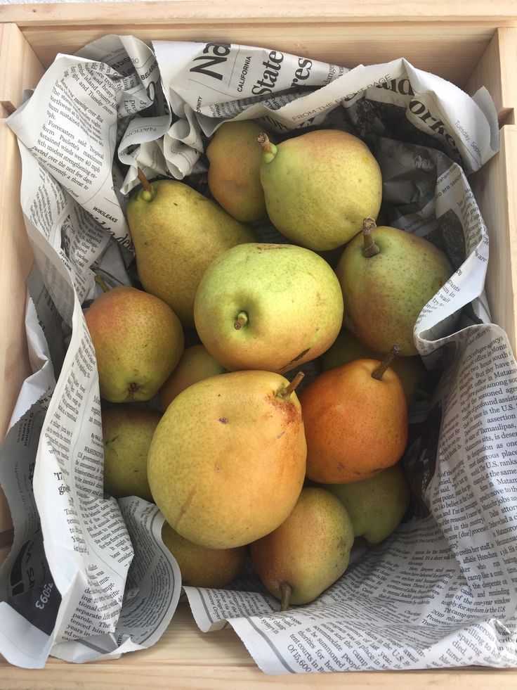 a wooden box filled with lots of different types of fruit on top of newspaper paper