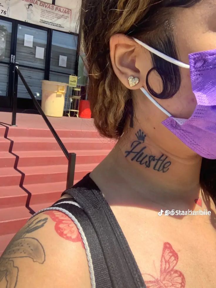 a woman wearing a purple face mask and tattoos on her neck with the word hustle written on it