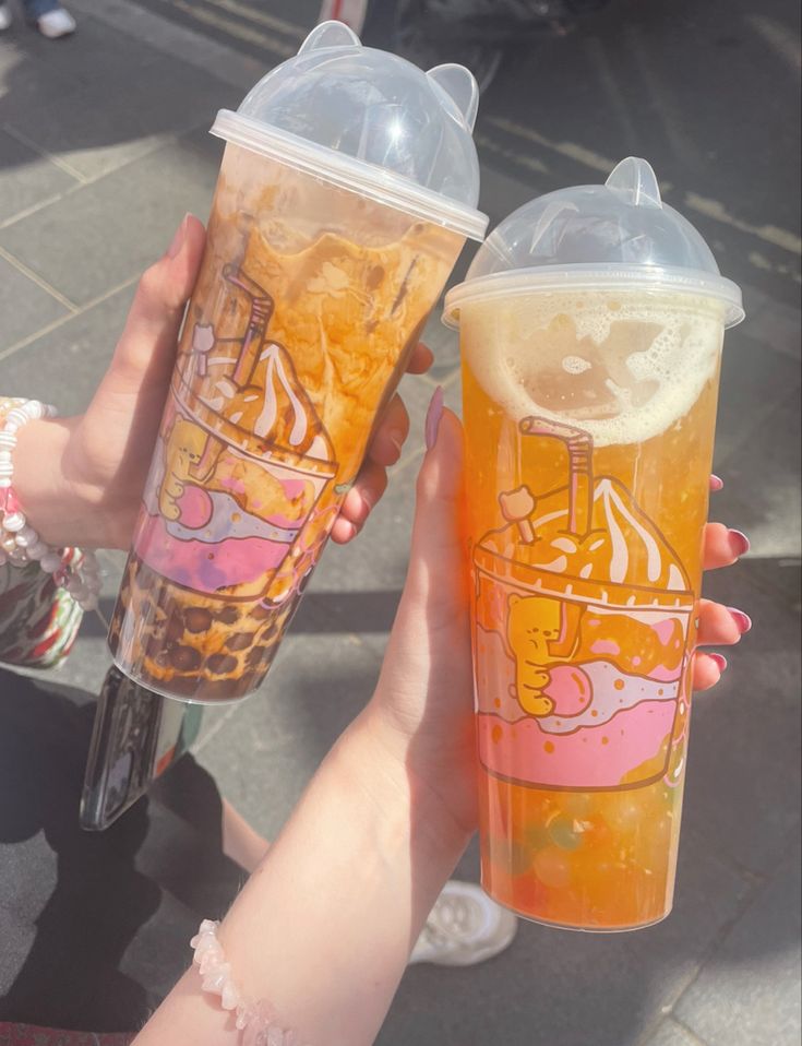 two people holding up cups with drinks in them