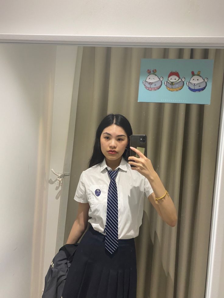 a woman taking a selfie in front of a mirror wearing a skirt and shirt