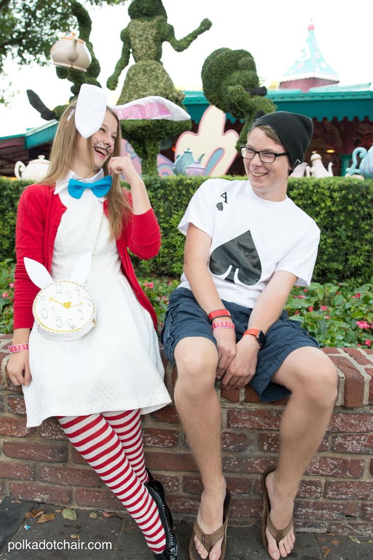 two people are sitting on a brick wall and one is wearing a white bunny costume