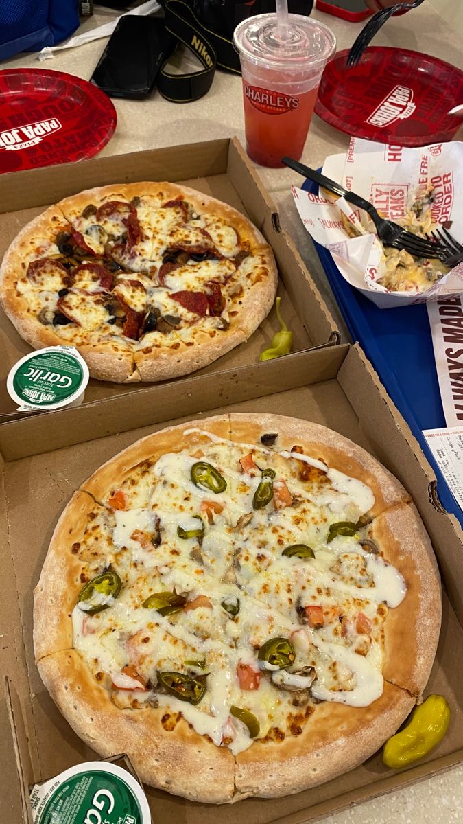 two pizzas in boxes on a table