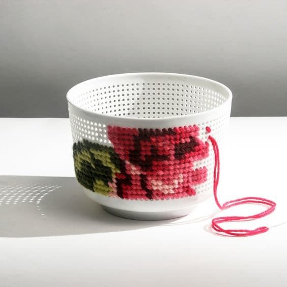 a white bowl with flowers on it and a red string hanging from the bottom to the side