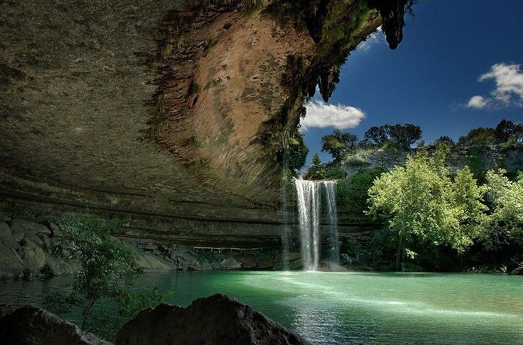 there is a large waterfall in the middle of this lake and it's green water