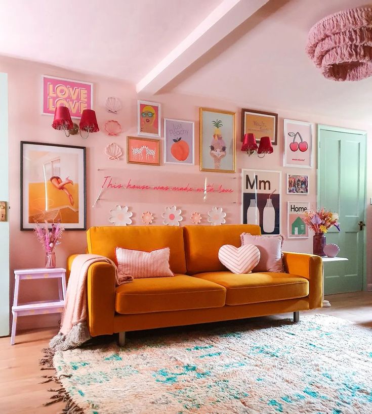 a living room with pink walls and pictures on the wall above the orange couches