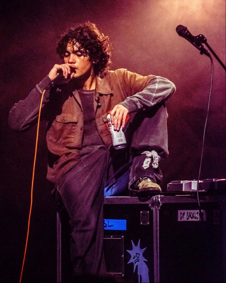 a man sitting on top of a stage holding a microphone