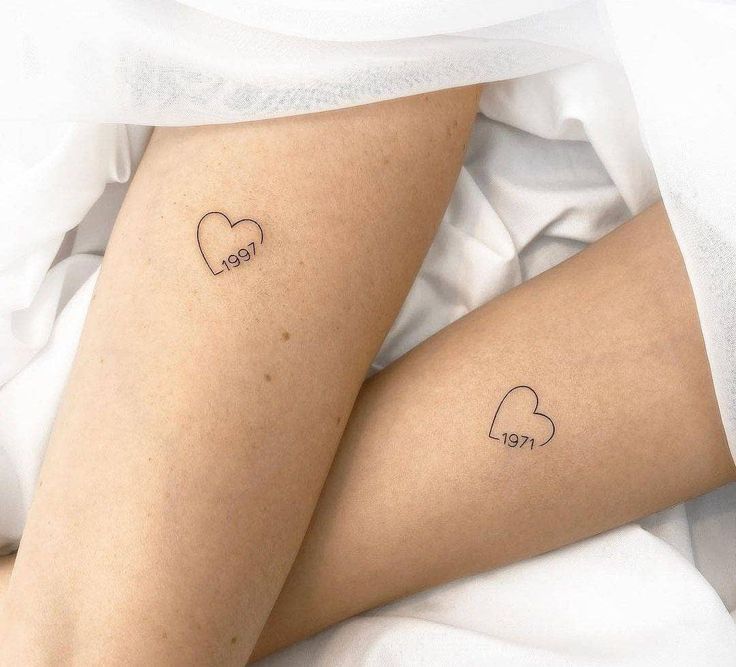 two small tattoos on the legs of someone laying in bed with white sheets and pillows