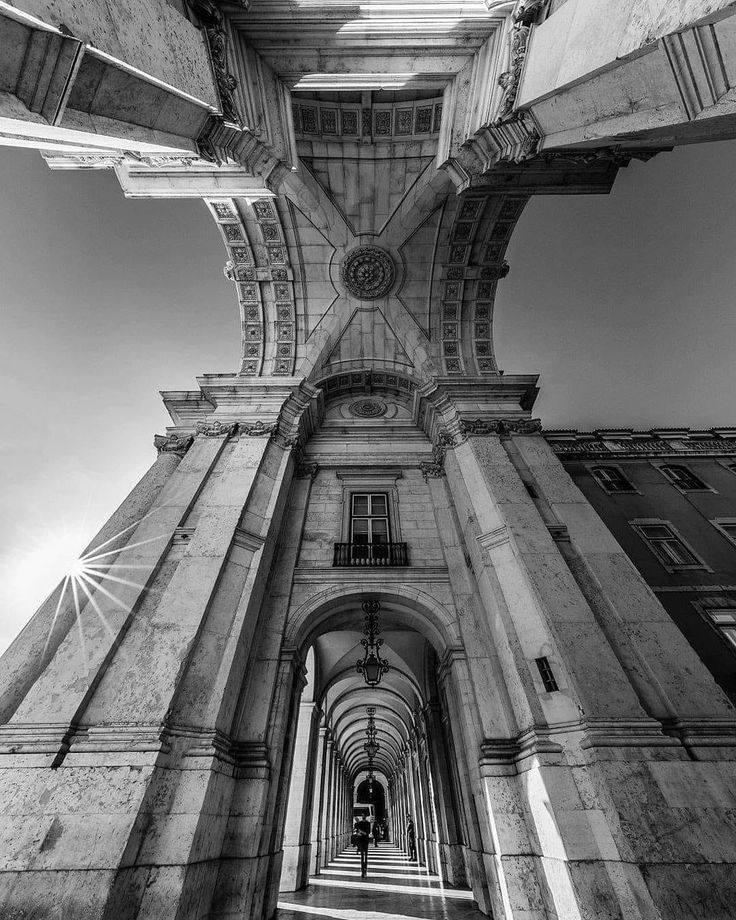 black and white photograph of an arch in the middle of a building with sunlight streaming through it