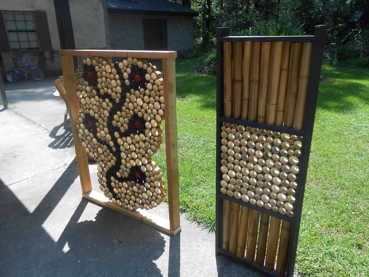 two wooden sculptures with holes in them on the sidewalk next to some grass and trees