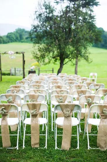 rows of white folding chairs with burlap sashes