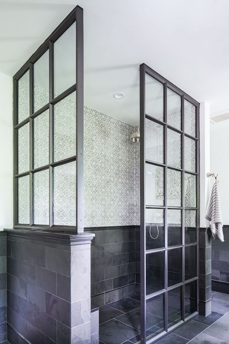 a black and white tiled bathroom with glass partitions on the wall, tile floor