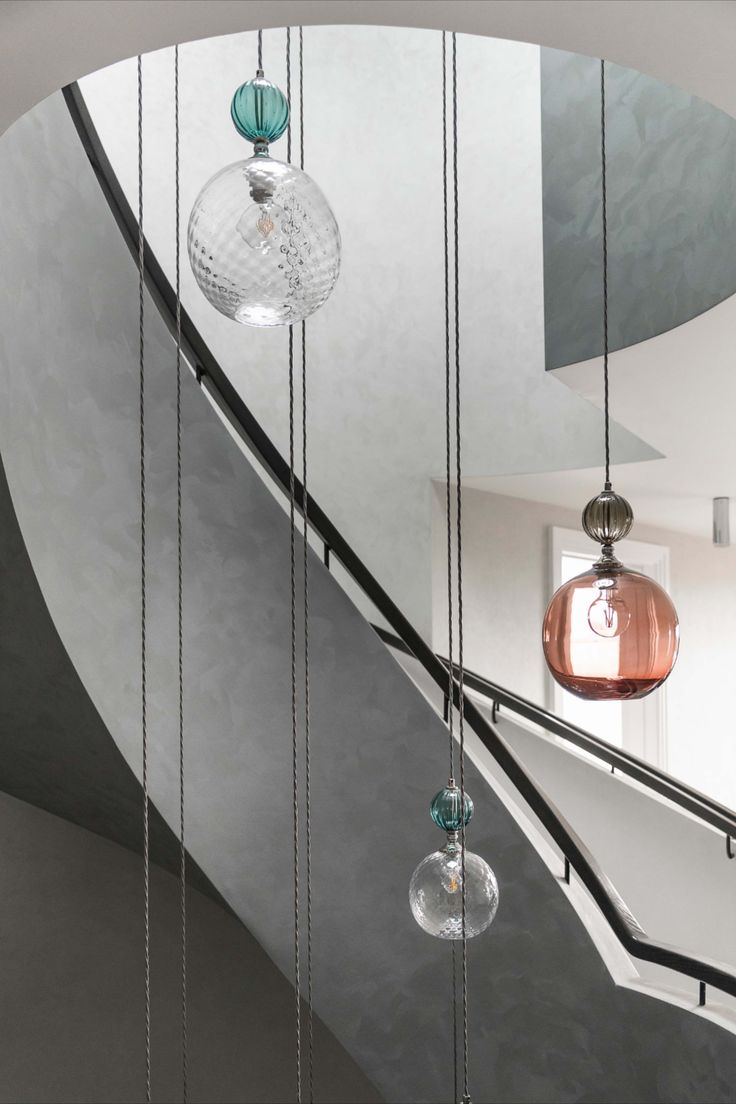 some glass balls hanging from the side of a stair case next to a spiral staircase