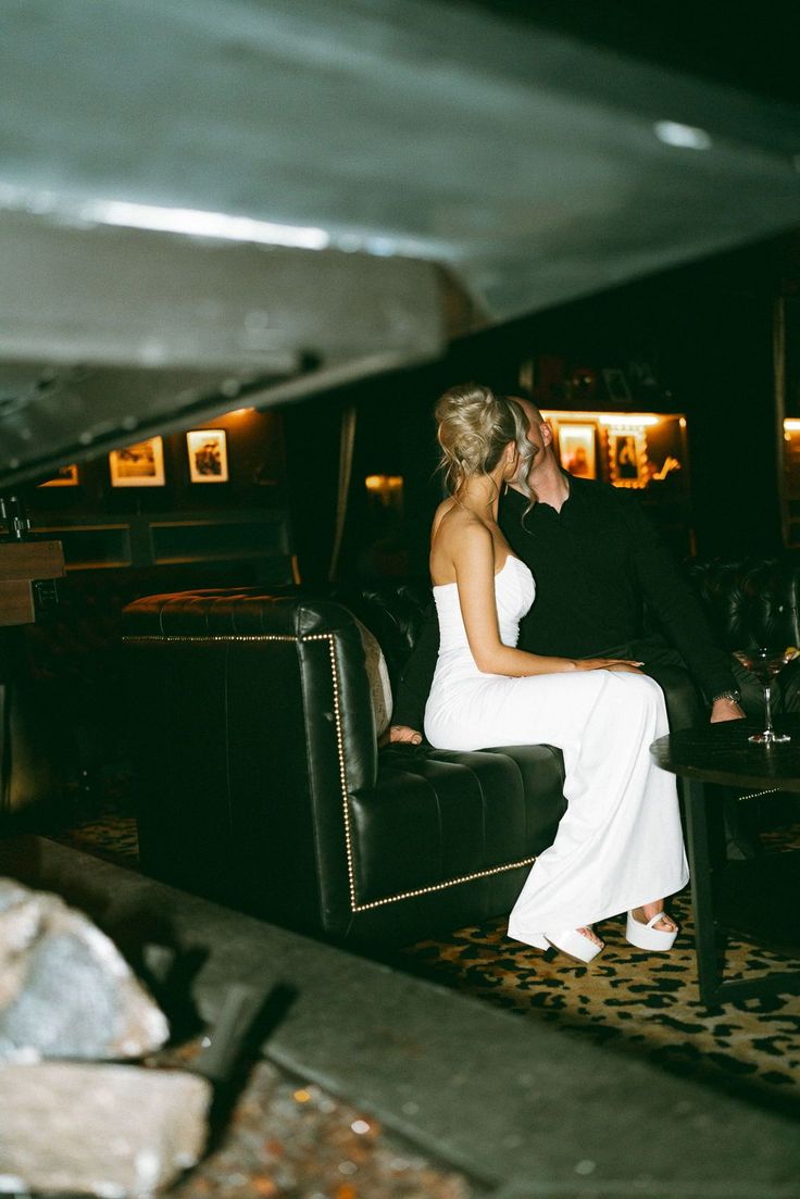 a bride and groom sitting on a couch in a dimly lit room