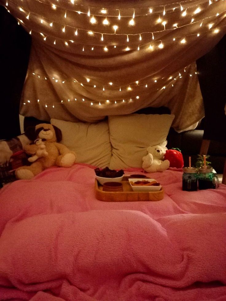 a bed covered in pink sheets and lights