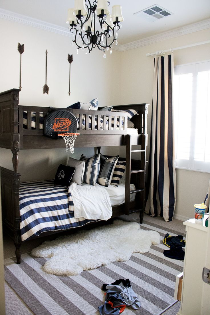 a bedroom with a bunk bed, striped rugs and a chandelier hanging from the ceiling