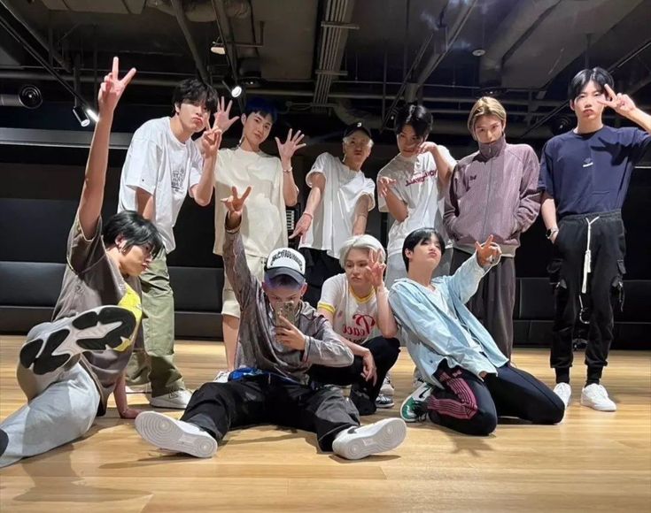 a group of young men standing and sitting on top of a wooden floor next to each other