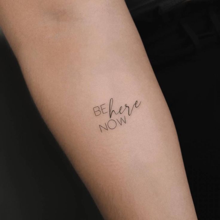 a person with a tattoo on their arm that says, be here now