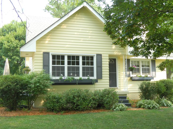 a small yellow house with black shutters