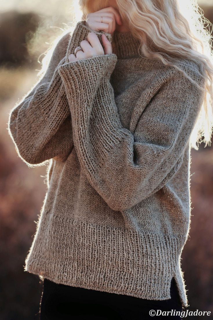 a blonde woman with long hair wearing a sweater and black pants is posing for the camera