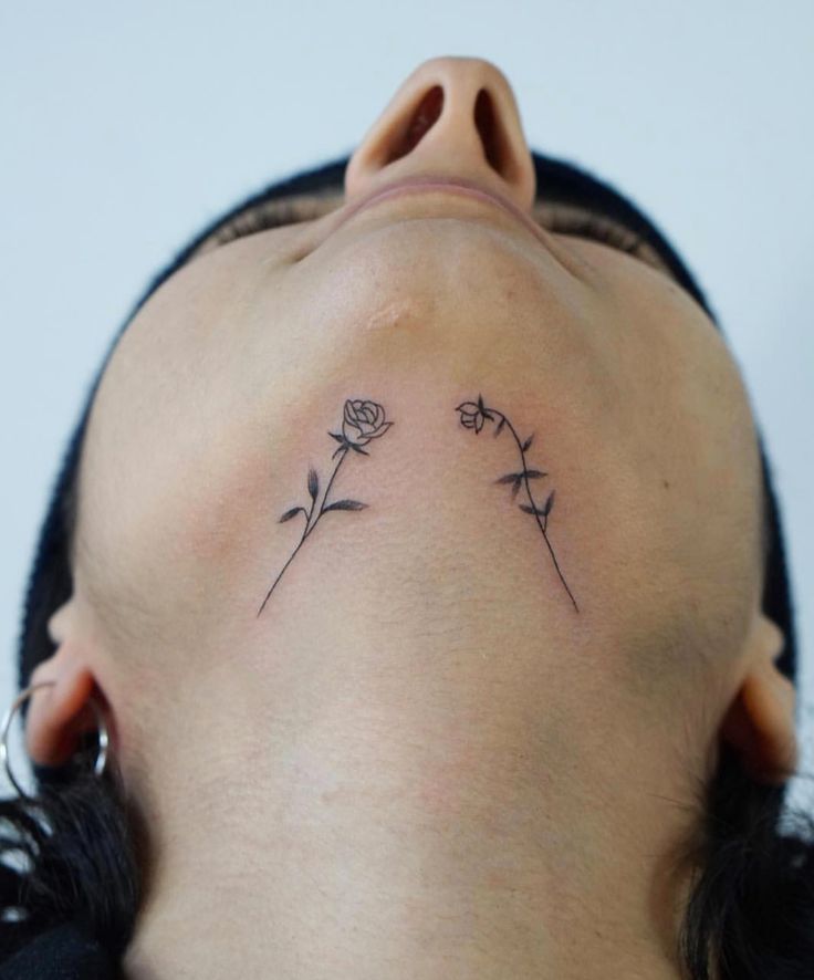 a woman's neck with three small flowers on her left side, behind her head