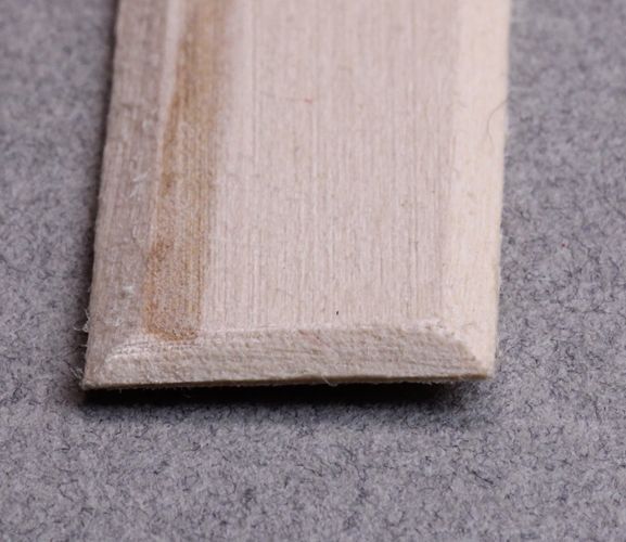 a piece of wood sitting on top of a gray floor next to a white wall