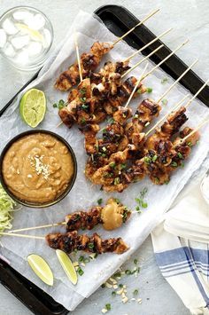 chicken skewers with guacamole sauce and limes on the side