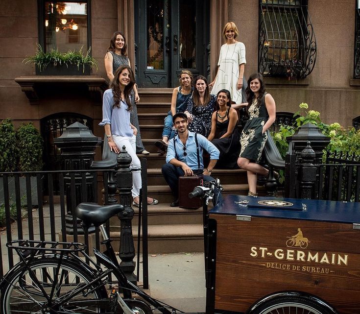 a group of people posing for a photo in front of a building with a horse drawn carriage