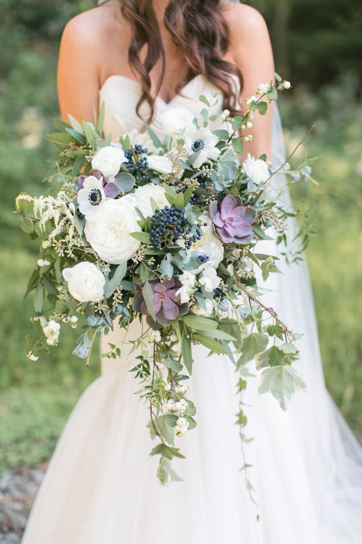 a bride holding a bouquet of white and purple flowers