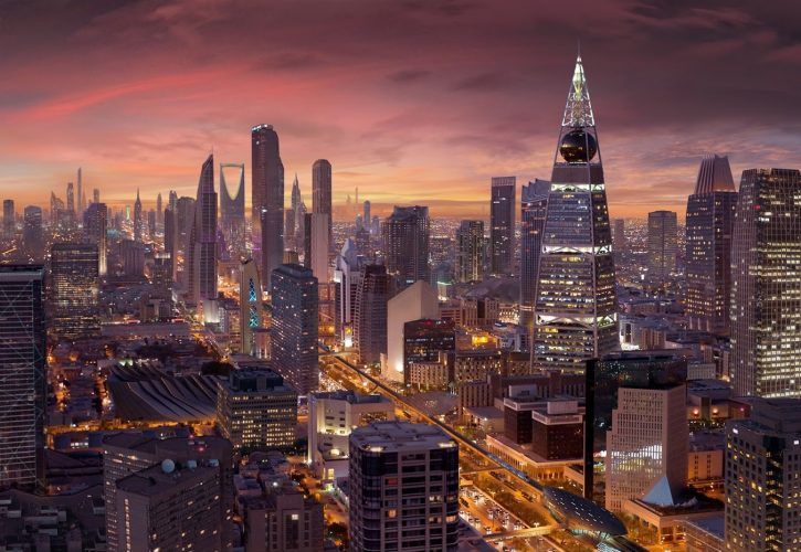 an aerial view of a city at night with skyscrapers lit up in the background