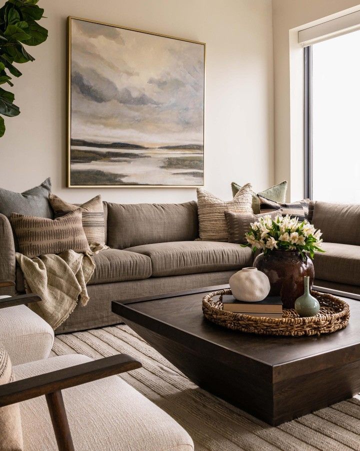 a living room filled with furniture and a large painting on the wall above it's coffee table