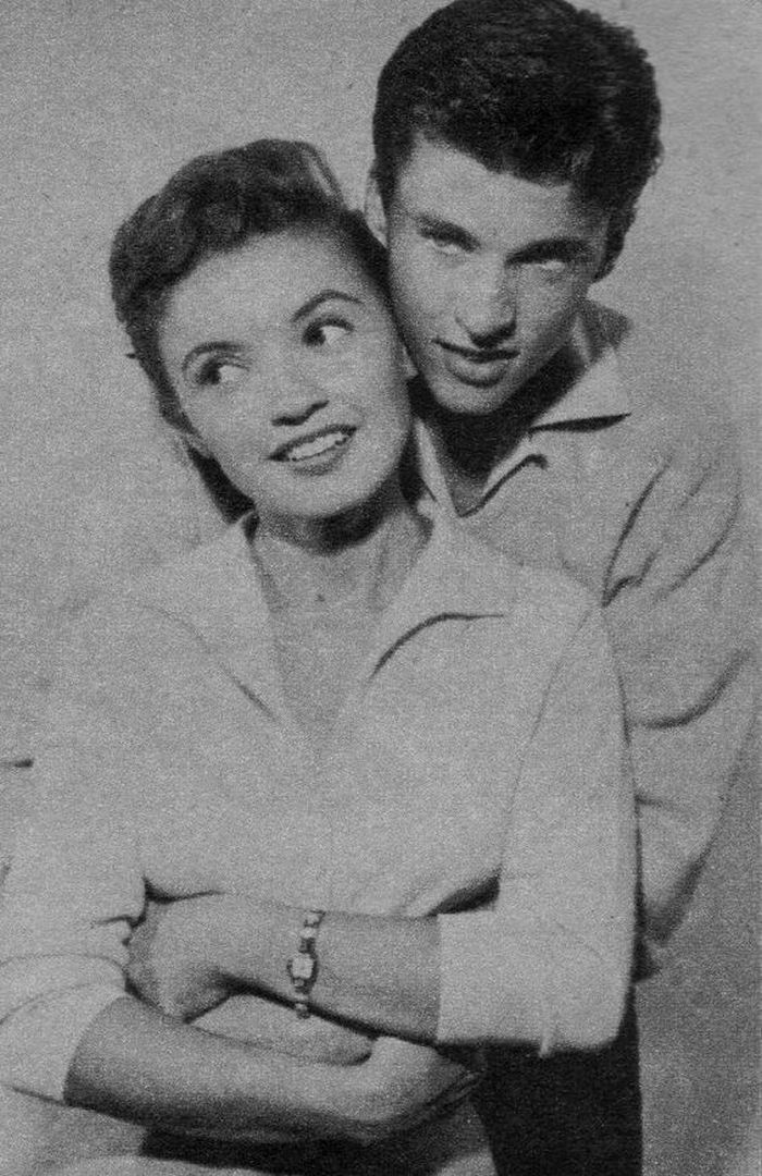 an old black and white photo of a man hugging a woman's head with her arms crossed