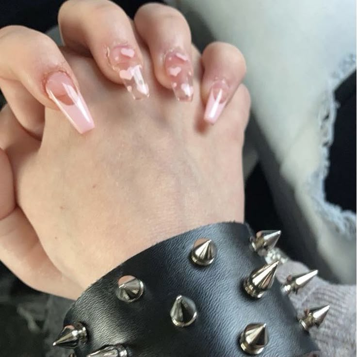 a woman's hand with pink nail polish and spikes on her wrist, holding onto a black leather bracelet