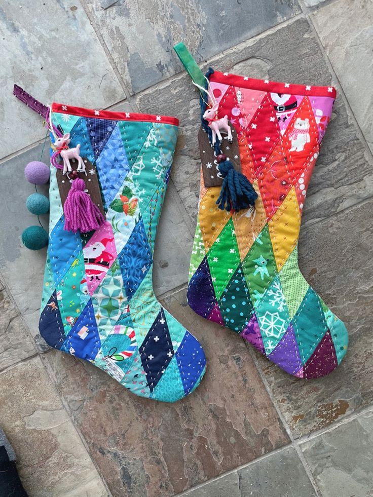 two colorful christmas stockings with tassels hanging from them on the floor next to each other