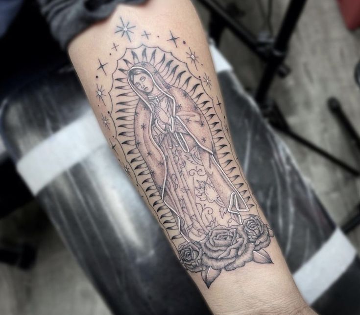 a tattoo on the arm of a person with a rosary and roses in front of her