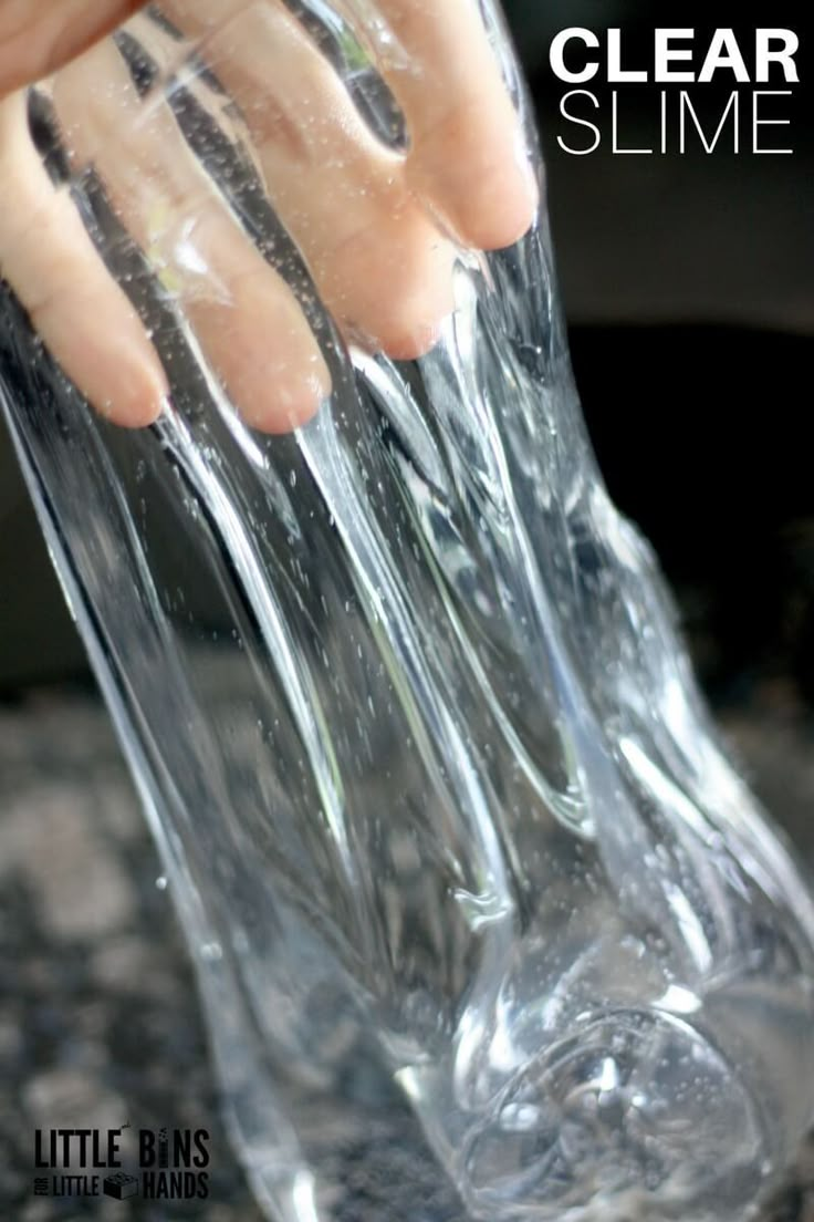 someone is pouring water into a clear glass vase with their hand on the top and bottom