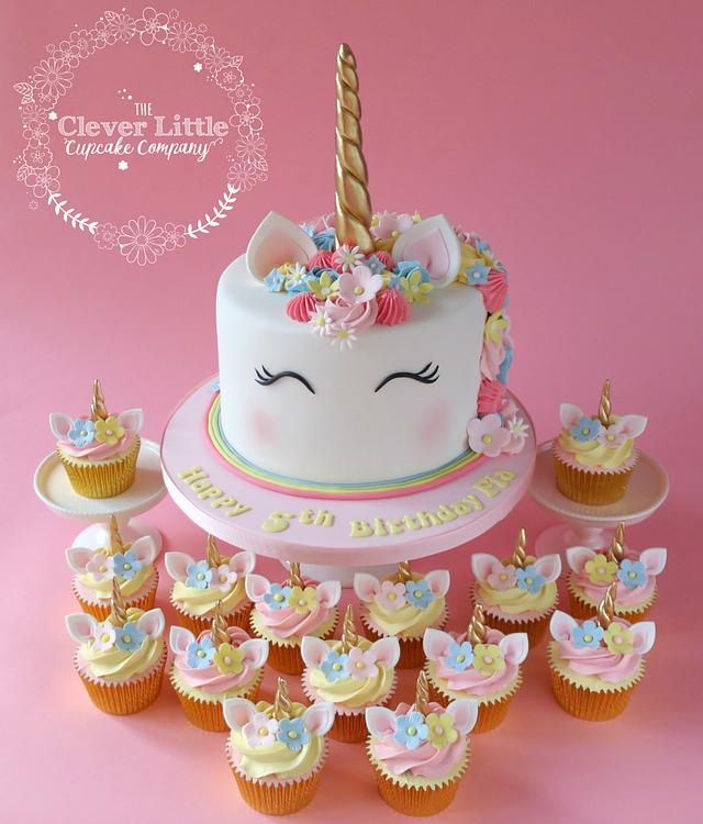 a birthday cake surrounded by cupcakes on a pink background