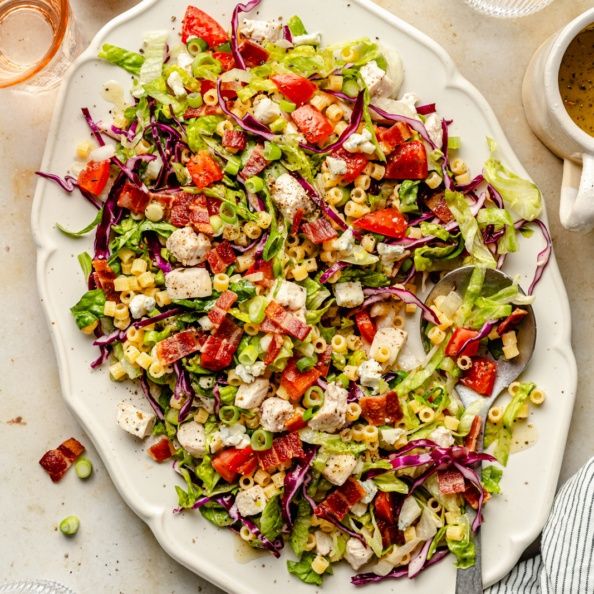 a white plate topped with a salad next to cups and sauces