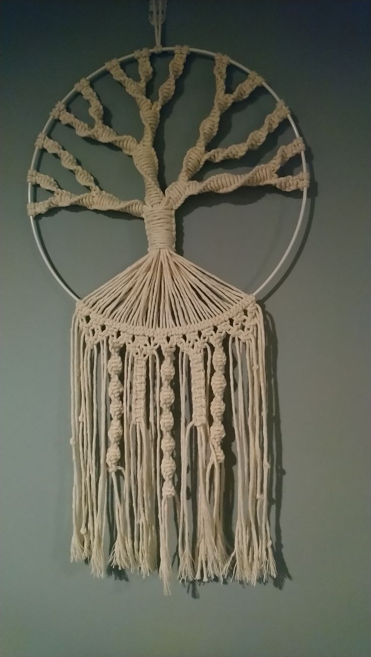 a white macrame hanging on the wall with a tree of life in it