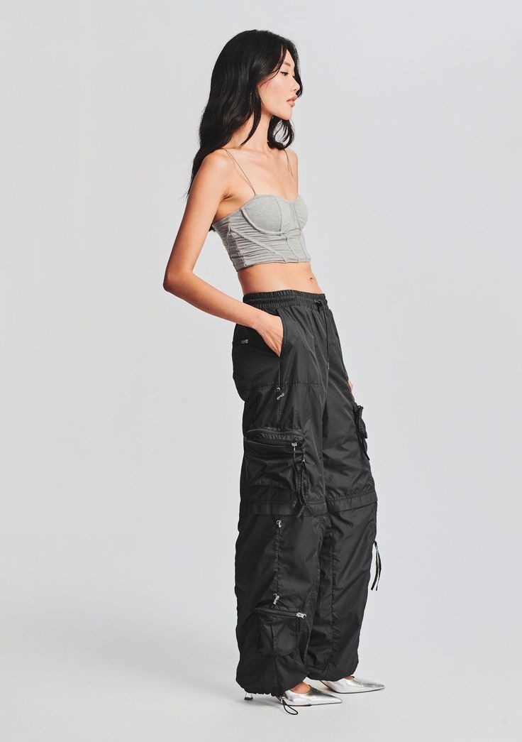 Baggy silhouette track pants with 3D side panel pockets, metal and zipper anglet embellishments. Double back welt pockets, and an adjustable ruched gathered drawstring hem. Shown here in Black. 100% Polyester Made in China She is 5'10" wearing size S He is 6'2" wearing size L Style No. 2755-14 Ruched Pants, Australia Clothes, Cut Out Top, Baggy Pant, Cargo Pant, Drawstring Pants, Corset Top, Denim Pant, Track Pants