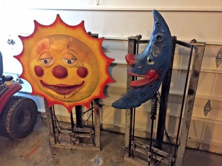 two sun and moon masks sitting next to each other on metal racks in a garage