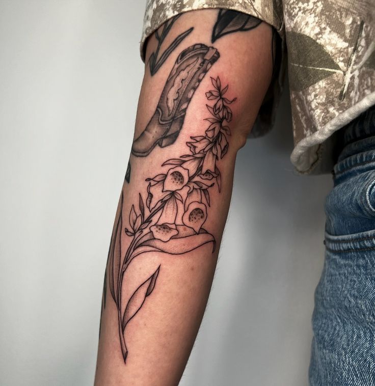 a person with a tattoo on their arm holding a knife and some flowers in front of them