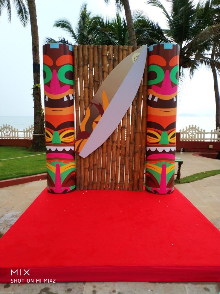 a large knife sitting on top of a red rug next to a wooden fence and palm trees